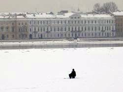 A fisherman in the middle of the frozen Neva river in winter